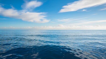 Obraz premium Calm ocean horizon under a bright blue sky with scattered clouds