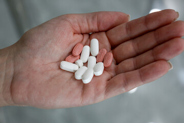 close up of a woman holding a pills in hand