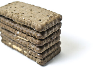 Photo of 3 or three black biscuit with peanut cream and sugar on the topping isolated on white background. Stack. Close up view.