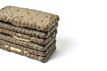 Photo of 3 or three black biscuit with peanut cream and sugar on the topping isolated on white background. Stack. Close up view.