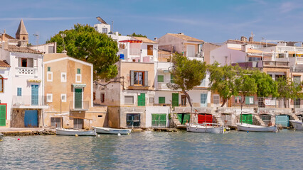 long shot of fishing boats and houses at the harbor of portocolom on mallorca, spain