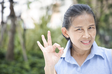 Happy smiling Asian middle aged old woman showing approving, passing, good, yes, go for it, good to...