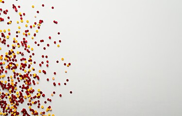 Red, orange, yellow sprinkles scattered on a white background, leaving ample copy space.