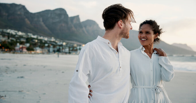 Vacation, travel and interracial couple embrace at ocean for love, care and healthy relationship. Beach, happy man and woman outdoor for summer holiday, tourism or romantic date with partner for chat