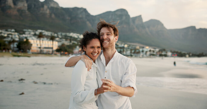 Beach, happy interracial couple and holding hands for love, trust and healthy relationship. Seashore, man and woman hug outdoor for summer holiday, travel and romantic date with partner for support