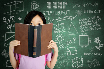 Asian schoolgirl peeking out of a book