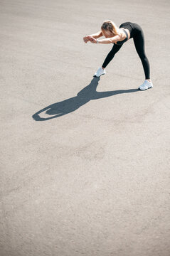 Sporty woman stretching and warming up legs for running