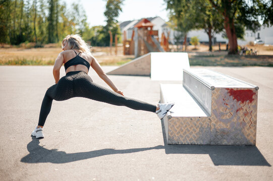 Back view of the woman stretching and warming up at urban stadium