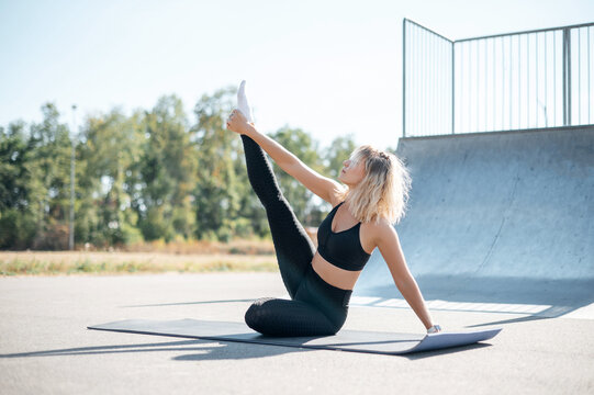 Blonde woman in sportswear sitting on yoga mat