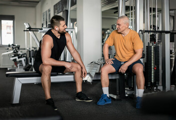 Two men talking and resting in a gym