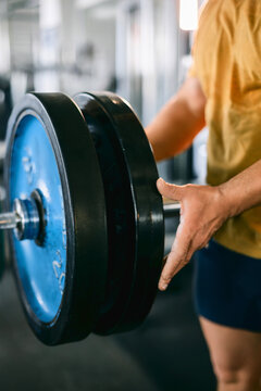 Close-Up of a Man Adjusting Weight Plates on a Barbell in a Gym