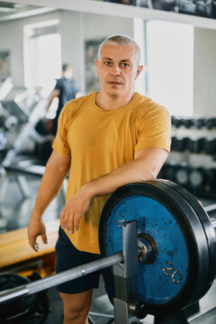 Senior Man Leaning on a Barbell in a Gym After Workout