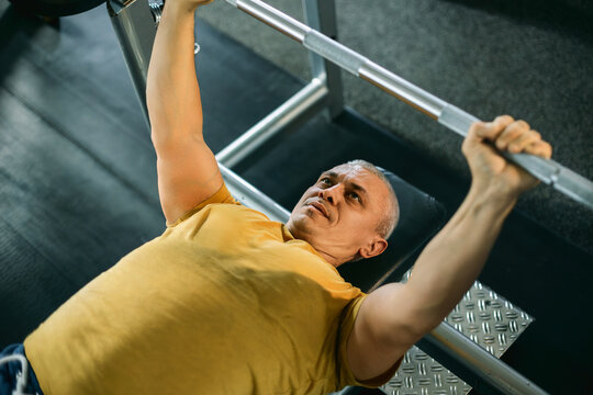 Focused Senior Man Lifting a Barbell in the Gym