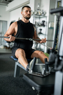 Muscular man performing cable row exercise in the gym