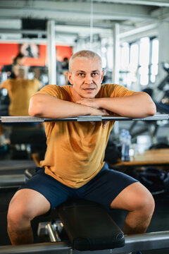 Athletic man confidently resting on barbell in gym setting