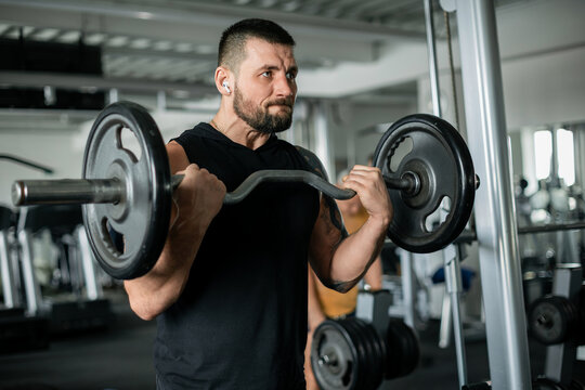 Determined man lifting a barbell in a gym workout