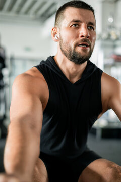 Focused muscular man training in a gym, sweating and determined