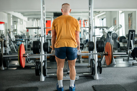 Man performing deadlifts with a barbell in a modern gym