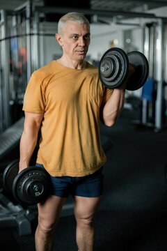 Focused man lifting dumbbells during a strength workout in the gym