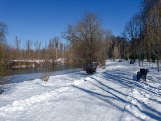 Spring landscape with river and melting snow under bright blue sky.