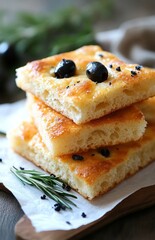 Fresh homemade focaccia bread with black olives and rosemary on paper