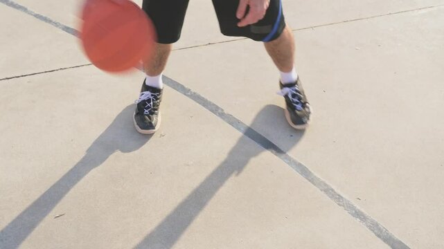 Young man practicing basketball dribbling on a concrete court