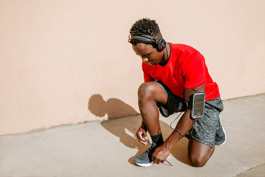 Athlete tying shoelaces and listening to music with headphones