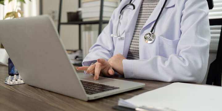 Virtual Healthcare and Patient Consultation. A medical professional navigating through online resources while consulting.
