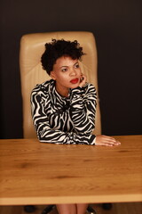 Naklejka premium Close portrait of curly businesswoman in black and white dress in office