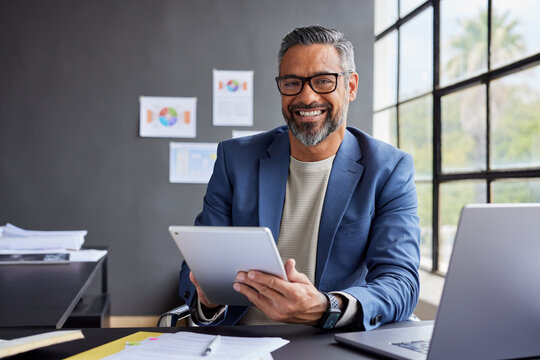 Smiling indian businessman working on tablet and smile