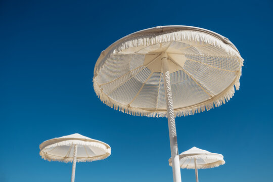 Summer beach andwhite umbrellas offering shade under the bright blue sky.