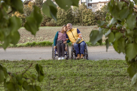 Two people with disabilities in wheelchairs are holding hands