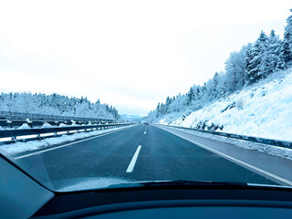 Winter Highway Drive Through Snowy Landscape Surrounded by Forested Hills