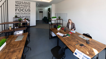 Modern co-working space with a woman working at a desk during daylight hours