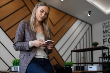 Woman checking her phone while sitting in a stylish cafe with modern decor in the afternoon