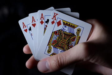 There are four playing cards in a hand that are being held
