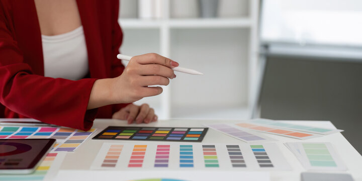 Color Theory and Graphic Design. A graphic designer focuses on a range of color swatches. - Powered by Adobe