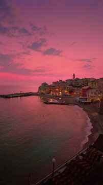 A wide-angle view of Bogliasco at sunset, with the village lights gently illuminating the charming coastal town. The calm sea and warm hues create a magical Mediterranean atmosphere