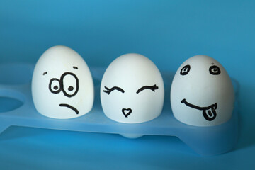 White eggs with painted smiley faces on a blue background.
