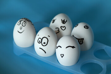 White eggs with funny smileys on a blue background. Space for an inscription.