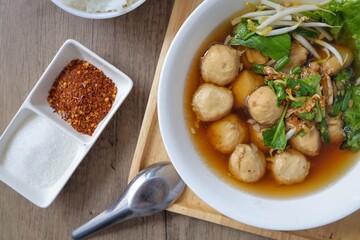 Close up of Thai style Meatball noodle soup  in white bowl with cooked rice
