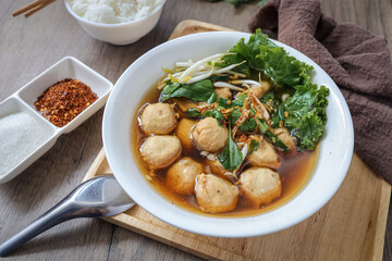 Thai style Meatball noodle soup  in white bowl with cooked rice