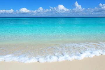 Fototapeta premium Crystal clear turquoise water gently laps against a sandy beach under a bright blue sky with fluffy white clouds