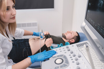 Female doctor doing ultrasound on male patient. Ultrasound of internal organs. Disease diagnostics