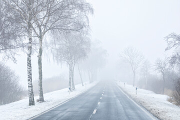 Obraz premium Rural road in winter, vanishing in mist