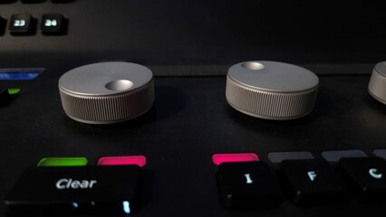 Close-up of a professional lighting control panel with illuminated buttons, rotary dials, and a...