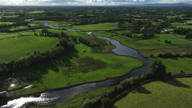 Finn River, County Monaghan, Ireland, September 2022. Drone orbits clockwise over a winding river, capturing lush green fields and picturesque countryside at the Irish border.
