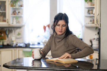 Cozy moments of reflection and learning over a warm drink in a sunlit kitchen while exploring the pages of a captivating book