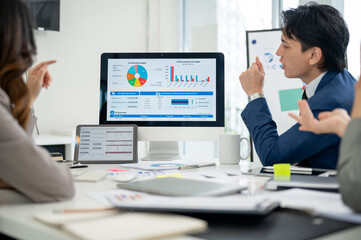 Businessman or male office worker talking about the financial report on monitor with his coworkers