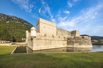 Ston, historic town in Peljesac peninsula in Croatia, Europe. Fortified walls and moat of an ancient European castle, with lush green backdrop and brilliant blue sky. A stately fortress. © Viliam